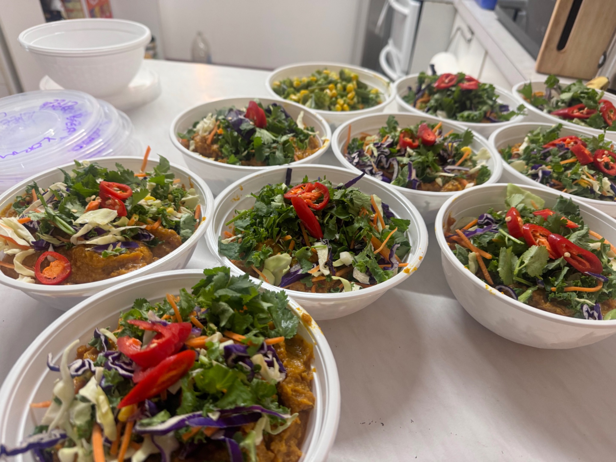 Prepared salad bowls on a kitchen bench