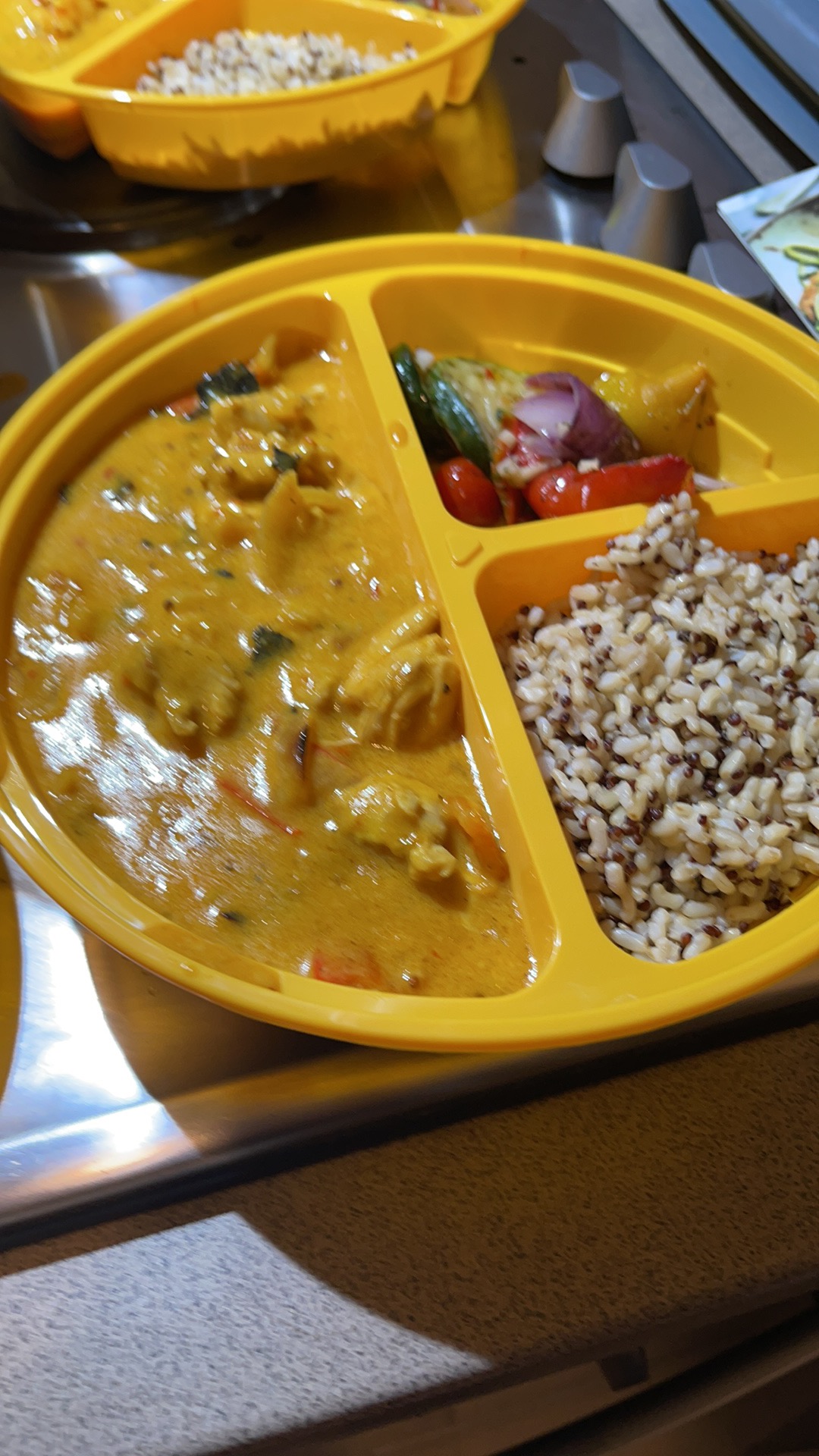 A curry-style meal with rice and sides in a divided container