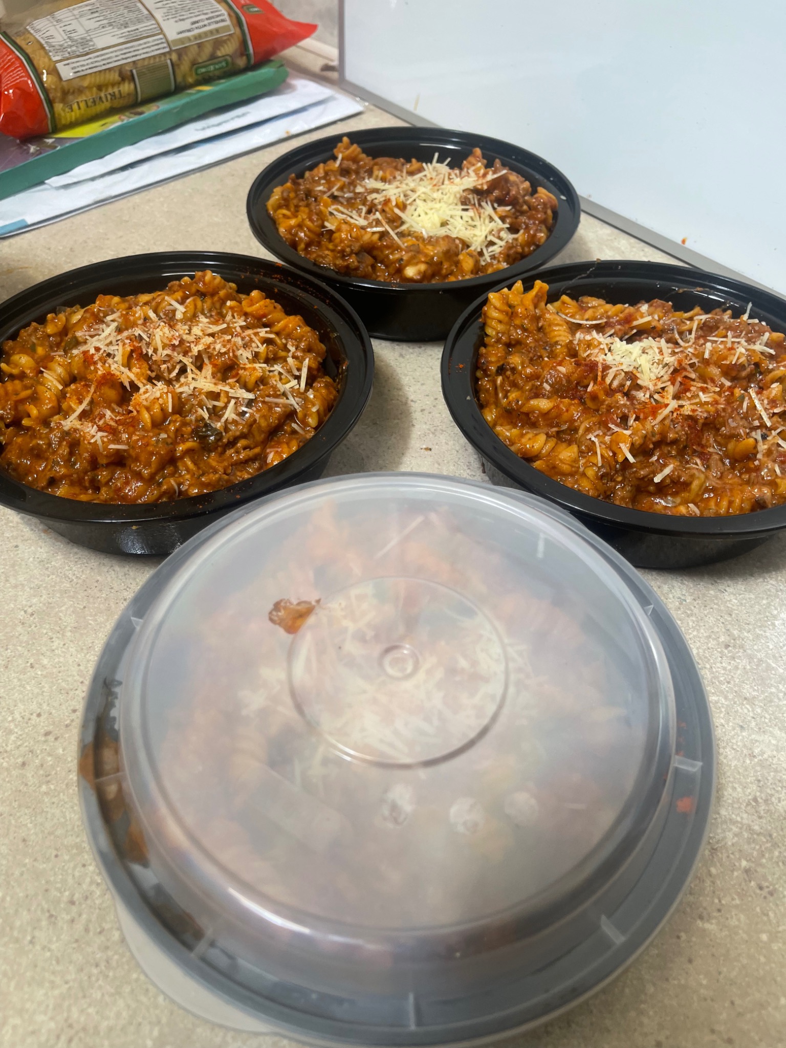 Actual spiral pasta meals with sauce and grated cheese in round containers